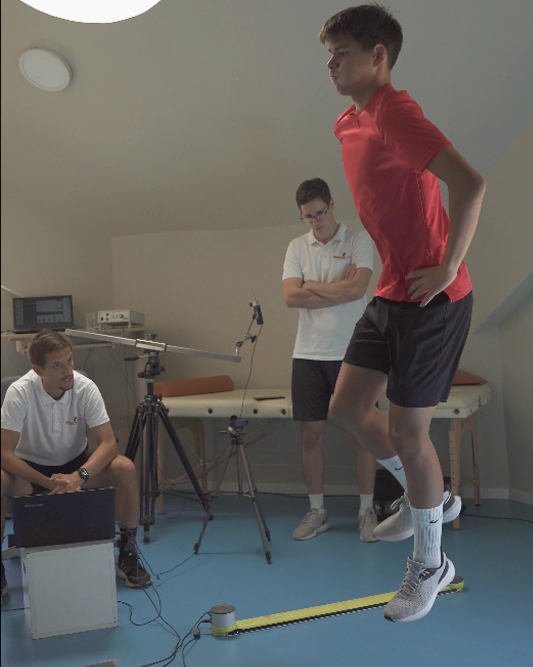 Sportista na Optojump letvicama tokom serije skokova; trener prati izmerene vrednosti na računaru.